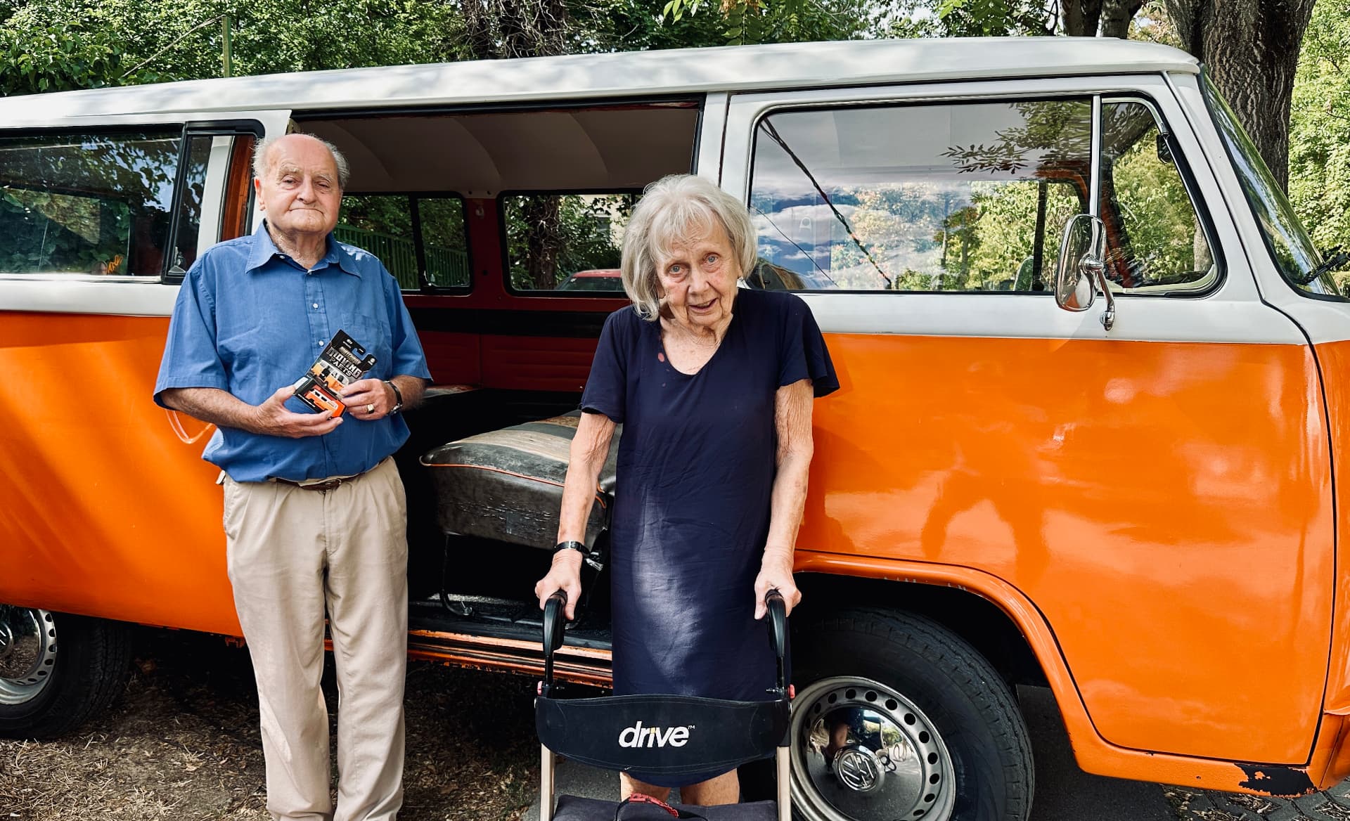 Mr. Thaly and his wife standing beside the real VW T2, holding the Matchbox model