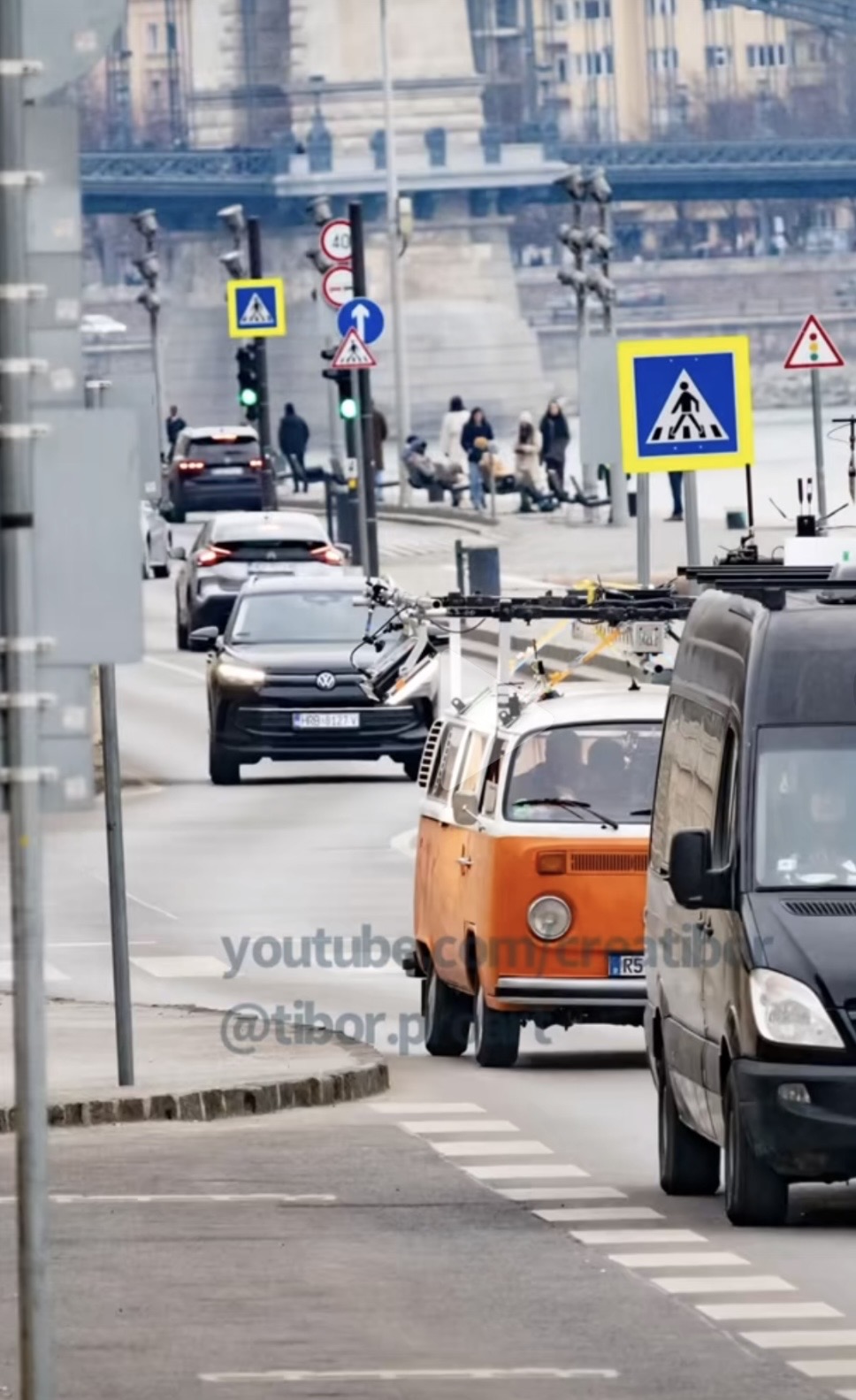 The orange VW T2 with camera rig driving on the Danube embankment near the Chain Bridge